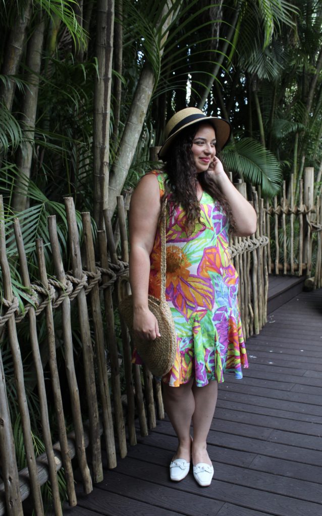 A woman wearing colorful dress and Target hat in front of palm trees.