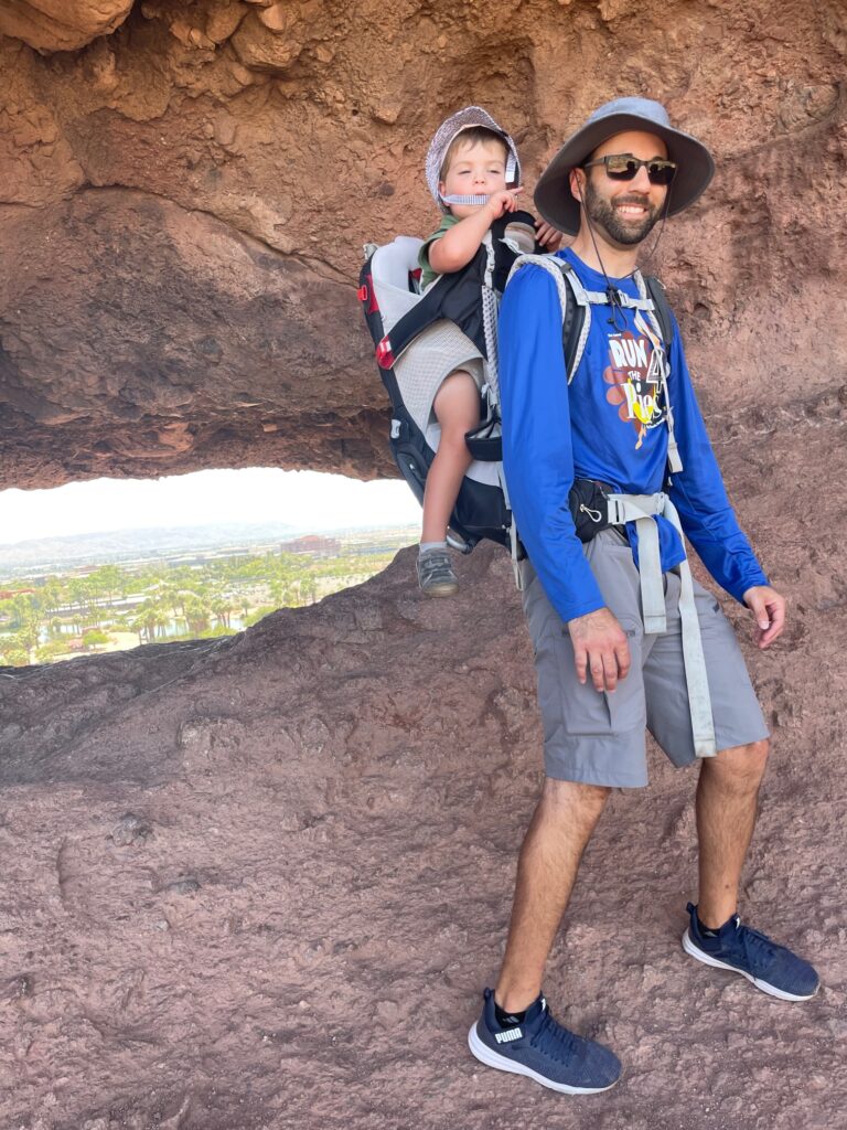 father and son in hiking carrier in front of Hole in the Rock in Scottsdale, Arizona
